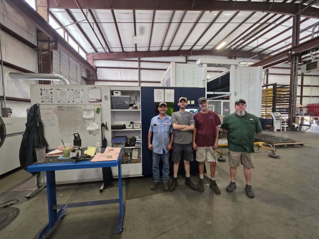 Laser cutting team standing in front of the equipment at MTC